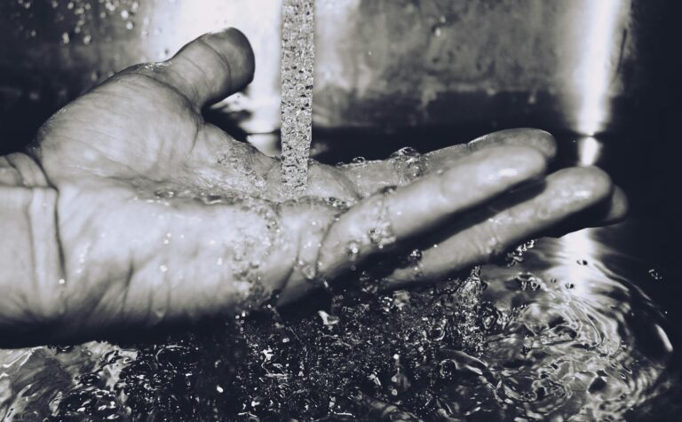 Black and white image of water flowing into a hand symbolizing clean water and sanitation