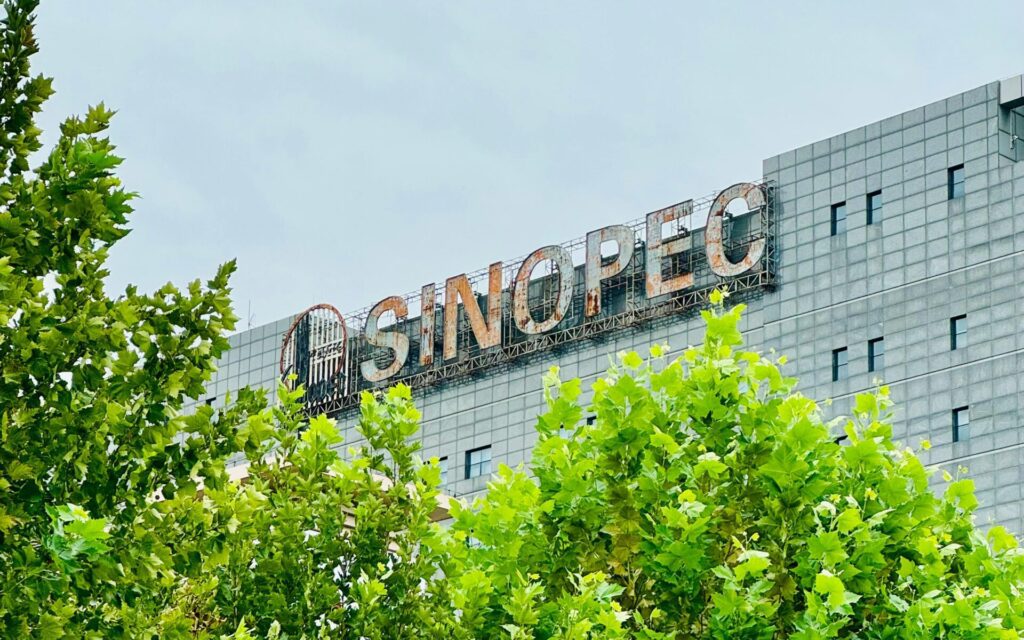Exterior view of the Sinopec building behind vibrant green trees in Tian Jin Shi, China.